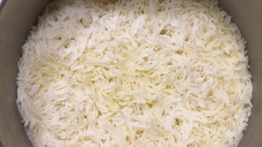 Taze pişmiş beyaz basmati pilavı tencerede pişiyor. Sıcak, kabarık tanecikleri yakından çek, yemek için mükemmel..