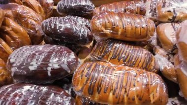Plastik filme sarılmış çeşitli yeni pişmiş hamur işlerinin yakın plan çekimi. Lezzetli çikolata ve fırın ortamında sergilenen buzlu çörekler..