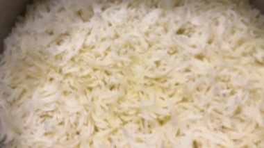 Taze pişmiş beyaz basmati pilavı tencerede pişiyor. Sıcak, kabarık tanecikleri yakından çek, yemek için mükemmel..