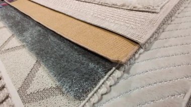 Mağaza ortamındaki çeşitli halı dokularının yakın görüntüsü. Satılık yumuşak ve desenli halıların ayrıntılı seçimi.