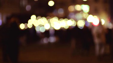 Bulanık şehir ışıkları insanlar gece yürürken canlı bir bokeh etkisi yaratıyor. Soyut kentsel arkaplan, projelere bir hareket ve atmosfer eklemek için mükemmel.