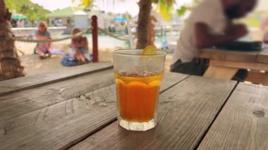 St.Maarten adasındaki bir plajda palmiye ağaçlarının altında dinlenirken bir pipetle serinletici, buzlu portakal kokteyli. Saint Martin, Karayipler 'in kuzeydoğusunda bir adadır..