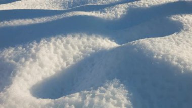 Kar yığınlarının güzel kış arkaplanı. Parlak güneş derin gölgeler ve sakin, soğuk bir atmosfer yaratır. Doğa, seyahat ya da mevsimlik projeler için mükemmel.