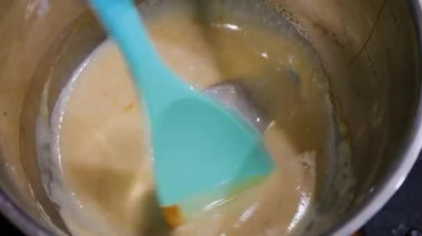 Kavanozda karamel hazırlığı. Karışık altın sıvı şeker. Güzel pişirme süreci. Kalın, tatlı karışımı karıştıran bir spatula..