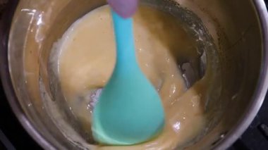 Kavanozda karamel hazırlığı. Karışık altın sıvı şeker. Güzel pişirme süreci. Kalın, tatlı karışımı karıştıran bir spatula..