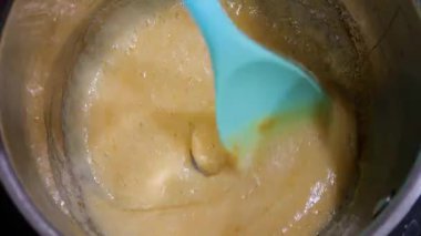 Kavanozda karamel hazırlığı. Karışık altın sıvı şeker. Güzel pişirme süreci. Kalın, tatlı karışımı karıştıran bir spatula..