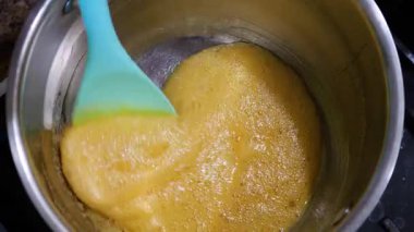 Kavanozda karamel hazırlığı. Karışık altın sıvı şeker. Güzel pişirme süreci. Kalın, tatlı karışımı karıştıran bir spatula..