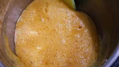 Kavanozda karamel hazırlığı. Karışık altın sıvı şeker. Güzel pişirme süreci. Kalın, tatlı karışımı karıştıran bir spatula..