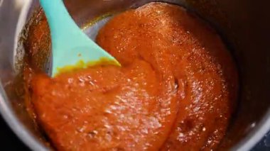 Zengin, altın karamel bir tencerede fokurduyor. Kalın ve tatlı karışımı karıştıran bir spatula. Mutfakta ev yapımı tatlı hazırlığı..