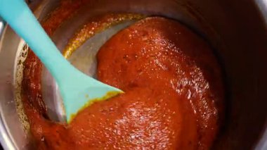 Zengin, altın karamel bir tencerede fokurduyor. Kalın ve tatlı karışımı karıştıran bir spatula. Mutfakta ev yapımı tatlı hazırlığı..