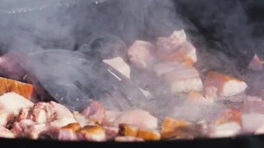 Sosis ve et sıcak bir tavada cızırdıyor. Buhar yükselirken yemek pişirme işlemini yakından çek. Sokak yemekleri hazırlanıyor..