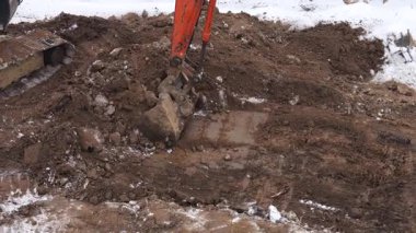 Bir kazıcı bir inşaat sahasında kazı çalışması yapıyor. Kışın film çekmek.