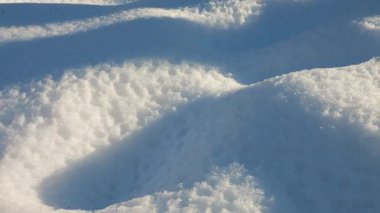 Kar yığınlarının güzel kış arkaplanı. Parlak güneş derin gölgeler ve sakin, soğuk bir atmosfer yaratır. Doğa, seyahat ya da mevsimlik projeler için mükemmel.