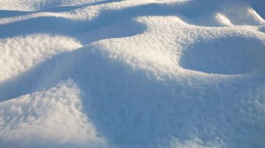 Kar yığınlarının güzel kış arkaplanı. Parlak güneş derin gölgeler ve sakin, soğuk bir atmosfer yaratır. Doğa, seyahat ya da mevsimlik projeler için mükemmel.