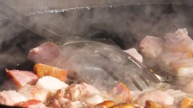 Sosis ve et sıcak bir tavada cızırdıyor. Buhar yükselirken yemek pişirme işlemini yakından çek. Sokak yemekleri hazırlanıyor..