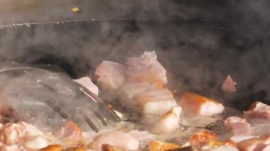 Sosis ve et sıcak bir tavada cızırdıyor. Buhar yükselirken yemek pişirme işlemini yakından çek. Sokak yemekleri hazırlanıyor..