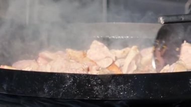 Sosis ve et sıcak bir tavada cızırdıyor. Buhar yükselirken yemek pişirme işlemini yakından çek. Sokak yemekleri hazırlanıyor..