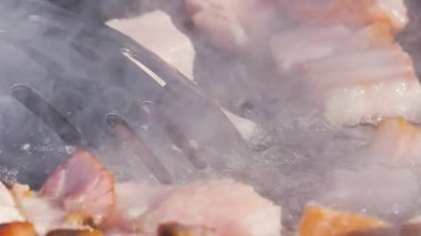 Sosis ve et sıcak bir tavada cızırdıyor. Buhar yükselirken yemek pişirme işlemini yakından çek. Sokak yemekleri hazırlanıyor..