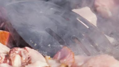 Sosis ve et sıcak bir tavada cızırdıyor. Buhar yükselirken yemek pişirme işlemini yakından çek. Sokak yemekleri hazırlanıyor..