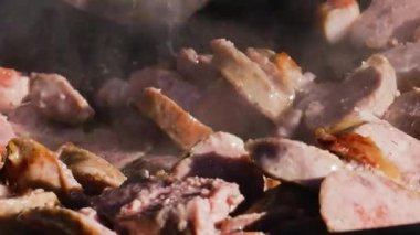 Sosis ve et sıcak bir tavada cızırdıyor. Buhar yükselirken yemek pişirme işlemini yakından çek. Sokak yemekleri hazırlanıyor..