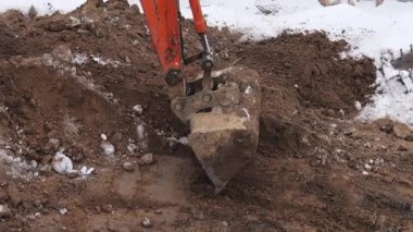 Bir kazıcı bir inşaat sahasında kazı çalışması yapıyor. Kışın film çekmek.