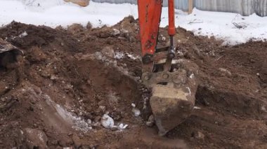 Bir kazıcı bir inşaat sahasında kazı çalışması yapıyor. Kışın film çekmek.