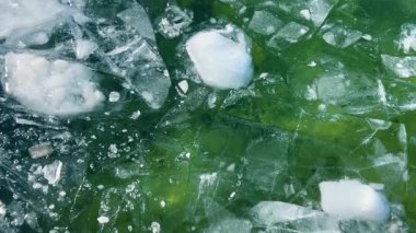 Buzlu su dokusu. Kırık buz parçaları yeşil suda yüzüyor. Soyut kış doğa sahnesi.