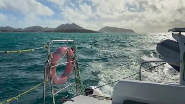 Karayip Denizi 'nde, Karayipler' in kuzeydoğusundaki Saint Martin adası yakınlarında bir tekne gezisi. Adanın kayalık kıyıları ve gemi dalgaları görünüyor..