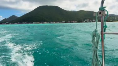 Karayip Denizi 'nde bir tekne gezisi. Saint Martin adası, Karayipler. Adanın kayalık kıyıları ve gemi dalgaları görünüyor..