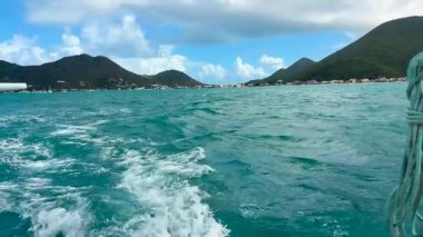 Karayip Denizi 'nde bir tekne gezisi. Saint Martin adası, Karayipler. Adanın kayalık kıyıları ve gemi dalgaları görünüyor..