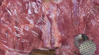 Hindi butunu ruloya hazırlıyorum. Eti metal bir çekiçle yapışkan filmle dövüyor..