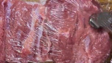 Hindi butunu ruloya hazırlıyorum. Eti metal bir çekiçle yapışkan filmle dövüyor..