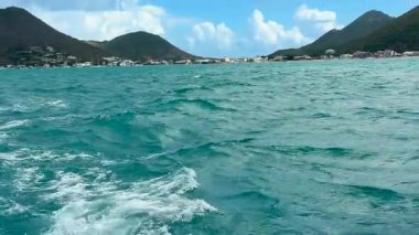Karayip Denizi 'nde bir tekne gezisi. Saint Martin adası, Karayipler. Adanın kayalık kıyıları ve gemi dalgaları görünüyor..