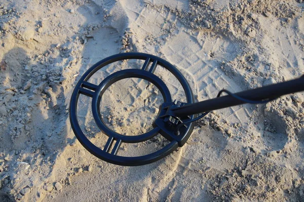 Metal detektör bobini kumda bir hazine arıyor.