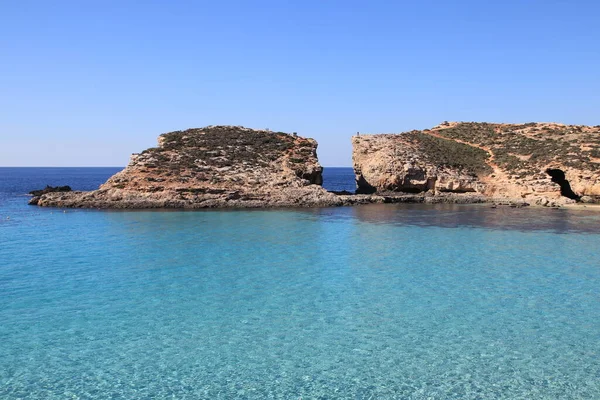 Blue Lagoon körfezinin yerel sahilden yakalanan kristal temiz su manzarası. Conimo, Malta.