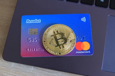 Berlin, Almanya - 21 Nisan 2021: Revolut Mastercard ve bilgisayarın üzerinde yatan bitcoin para birimi. Revolut hızlı, basit ve kolay bir satın alma, satma ve kripto para birimlerini elinde tutma yoludur..