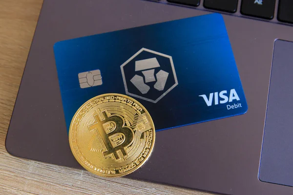Berlin, Almanya - 21 Nisan 2021: Crypto.com Midnight Blue Visa kartı ve dizüstü bilgisayarda duran bir bitcoin para birimi. Crypto.com acemi dostu bir şifreleme platformudur. .