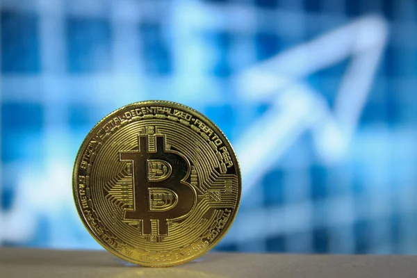 Bulanık mavi arkaplan ve bir ok ile Bitcoin BTC 'nin fiziksel bir sürümü.