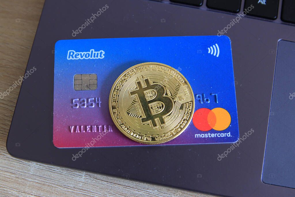 Berlin, Germany - April 21, 2021: Revolut Mastercard and a bitcoin currency lying on laptop.Revolut is a fast, simple, and easy way to buy, sell, and hold cryptocurrencies.