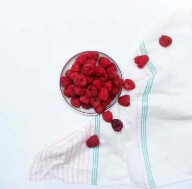 Bir fincan tabağı ve retro havluyla sulu ahududu. Güzel yaz kırmızı meyvesi.