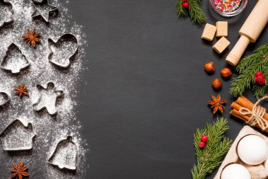 Siyah arkaplanda fotokopi alanı olan noel kurabiyeleri yapmak için gerekli form ve malzemeler.