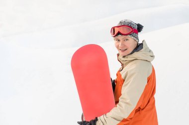 Kar yamacının arkasında gözlüklü bir kadın snowboardcunun portresi..