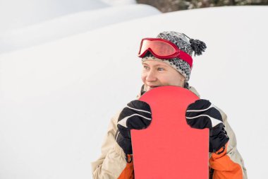 Kar yamacının arkasında gözlüklü bir kadın snowboardcunun portresi..