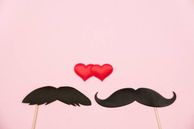 Sevgililer Günü lgbt, aşk, romantik konsept. Pembe arka planda çift bıyıklı kırmızı kalpler. Tebrik kartı. Düz konum, üst görünüm, kopyalama alanı.