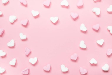 Beyaz ve pembe kalp şekilli şekerlemeler pembe arka planda fotokopi alanı ile.