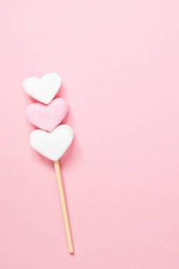 Beyaz ve pembe kalp şekilli şekerlemeler. Pembe bir arka planda tahta bir çubuk üzerinde. Fotokopi alanı olan..
