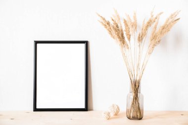 Kurumuş çiçekler ve ışık duvarına karşı minimalist tarzda bir fotofram.