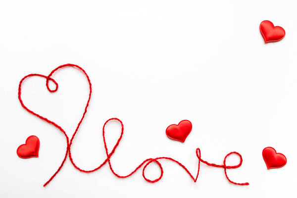 Valentine's day concept. Red heart and word love made from woolen rope on white background with copy space