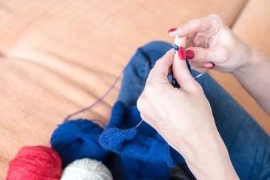 Mavi bir atkı ören kadın ellerinin yakın çekimi..