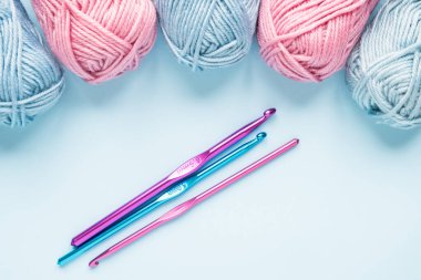 Mavi arka planda iplik yumakları olan çok renkli örgü kancaları..